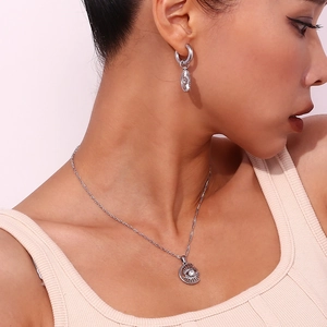 Detail of silver stainless steel moon and sun eye pendant necklace with matching earrings