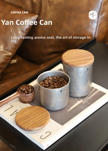 Close-up of matte stainless steel coffee canisters with wooden lids and measuring spoon