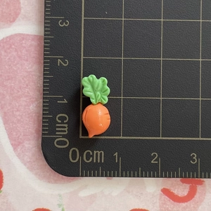 Detailed view of a 1.2cm orange resin carrot charm on a metric scale cutting mat