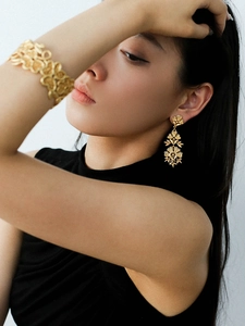 Close-up of vintage gold hollow flower tassel earrings and wide cuff bracelet set