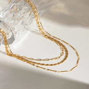 Detail of layered gold metal necklace featuring paperclip and rope chain textures