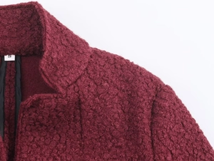 Detailed close-up of wine red curly wool fabric texture and S size label on coat collar