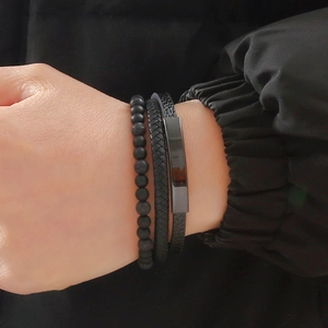 Close-up of men's multi-layer bracelet with black matte beads and braided leather cord