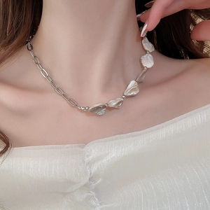Primo piano di una collana a catena argentata con perle barocche indossata da una modella