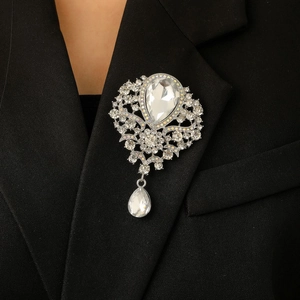 Detailed close-up of a vintage silver crown brooch with crystals on a black suit lapel