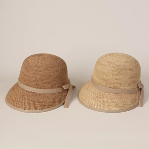 Close-up of fine raffia straw texture and satin bow detailing on elegant sun hats