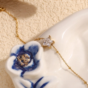 Macro shot of an 18K gold plated star pendant with cubic zirconia on a delicate bead chain