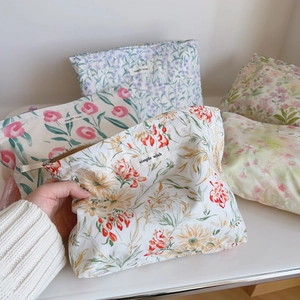Détail de quatre trousses de maquillage en coton fleuri avec étiquette tissée
