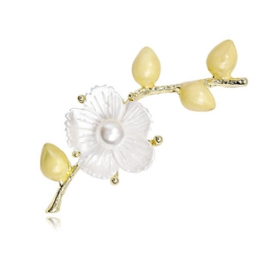 Close-up of golden branch brooch with white shell flower and elegant central pearl