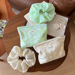 Detailed shot of bubble texture makeup bag and scrunchie set in cream and mint green