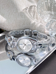 Detail view of a vintage silver bangle watch with oval dial resting on a reflective tray