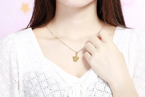 Primo piano di una collana con pendente ad angelo dorato e lettera S su catena sottile