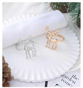 Close-up of gold and silver reindeer napkin rings on a white plate with pine cones