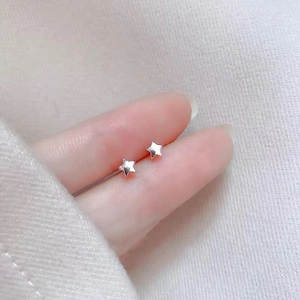 Macro view of 925 sterling silver star stud earrings on a fingertip for scale