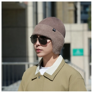 Détail du bonnet en tricot marron clair avec cache-oreilles en peluche et étiquette latérale