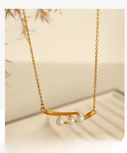 Gros plan d'un collier en or avec trois perles blanches sur un pendentif élégant