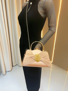 Close-up of champagne pleated evening clutch with golden handle and chain strap