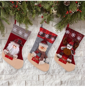 Three festive Christmas stockings with Santa, snowman and reindeer on white brick wall