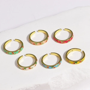 Detail view of six colorful enamel floral rings on a white stone display stand