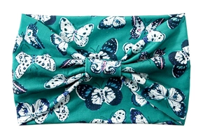Detailed view of dark green wide headband with butterfly print and knotted elastic fabric