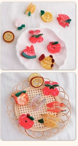 Close-up of colorful resin fruit hair clips including strawberry and peach designs
