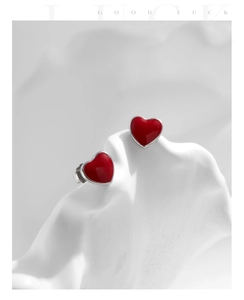 Macro shot of red heart stud earrings in s925 silver on a white minimalist stone stand