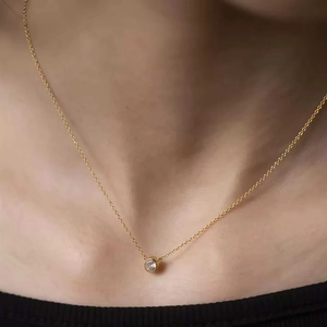 Dettaglio di una collana con ciondolo a chicco d'oro 18K indossata sulla clavicola