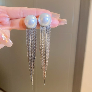 Macro detail of silver tassel earrings with white pearls showing the elegant metal chains