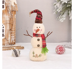 Detail of linen snowman plush with carrot nose and red plaid scarf in Christmas setting