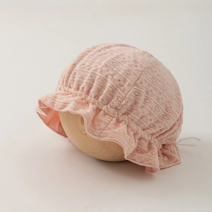 Detailed view of pink baby lace bonnet with floral embroidery on a wooden display