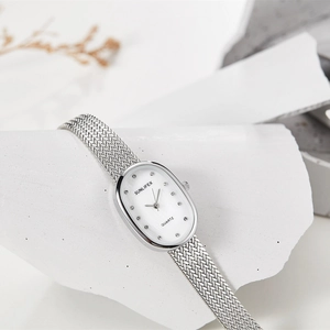Detail of silver oval quartz watch with rhinestone markers on white textured stone