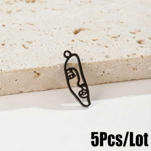 Detail view of five abstract face metal pendants resting on a beige textured stone base