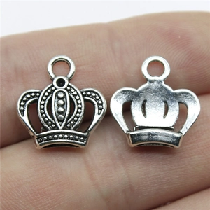 Silver crown charms for DIY jewelry making shown on finger for scale