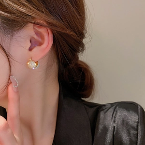 Detailed view of gold hoop earrings with zircon pavé sphere pendant on model