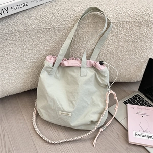 Detail of light green nylon tote bag with pink drawstring and woven shoulder strap