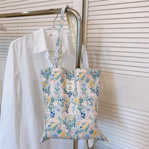 Detail of floral canvas tote bag with rabbit print hanging in a bright interior setting