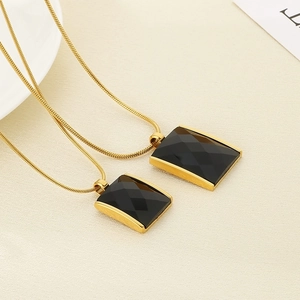 Detailed view of square black onyx pendants on elegant golden snake chain necklaces