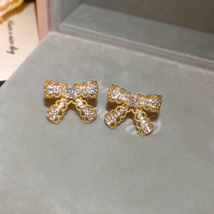 Detailed close-up of gold-plated bow earrings with sparkling cubic zirconia on velvet