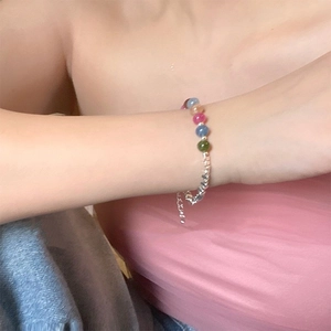Detail of colorful beads and silver metal cubes on a delicate bracelet worn on wrist