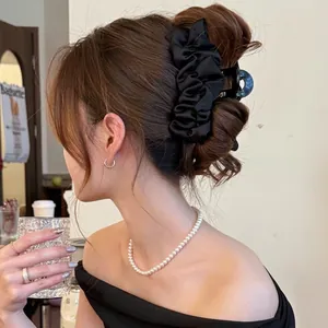 Pince à cheveux élégante en satin plissé noir portée sur un chignon sophistiqué
