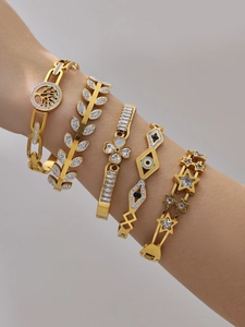 Close-up of five-piece gold-plated bracelet set with clover, leaf, and evil eye motifs