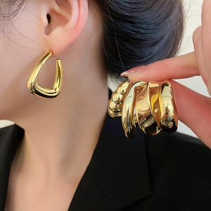 Macro shot of assorted chunky gold hoop earrings with pleated and braided textures