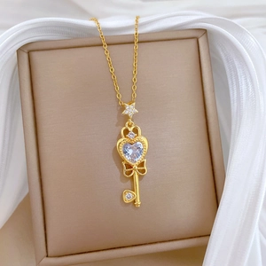Detailed close-up of a gold key necklace with blue heart gemstone on white silk fabric