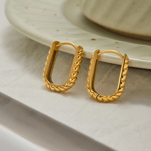 Detailed close-up of golden U-shaped hoop earrings with a twisted rope texture finish