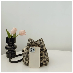 Detail shot of leopard print plush bucket bag with drawstring and smartphone for size