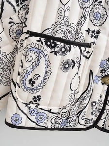 Detail of paisley floral quilted jacket with black piping and textured fabric finish