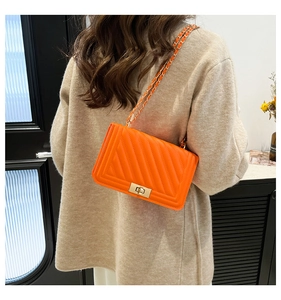 Close-up of orange V-quilted faux leather bag with gold chain strap and square metal lock