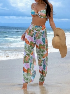 Detailed view of tropical print bikini top and matching wide-leg trousers on beach