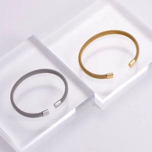 Detail of woven stainless steel mesh bracelet in gold and silver finish with metal end caps