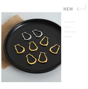 Detailed view of geometric titanium steel earrings in gold and silver on a black tray